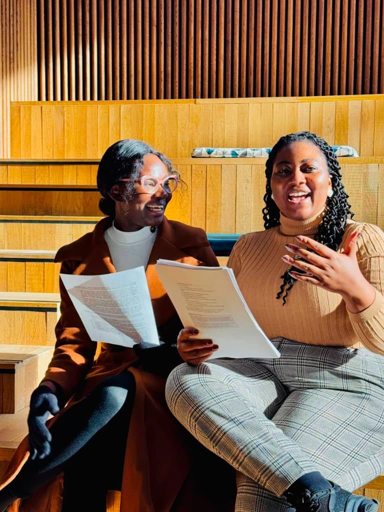Young women discussing documents in a leadership and academic setting